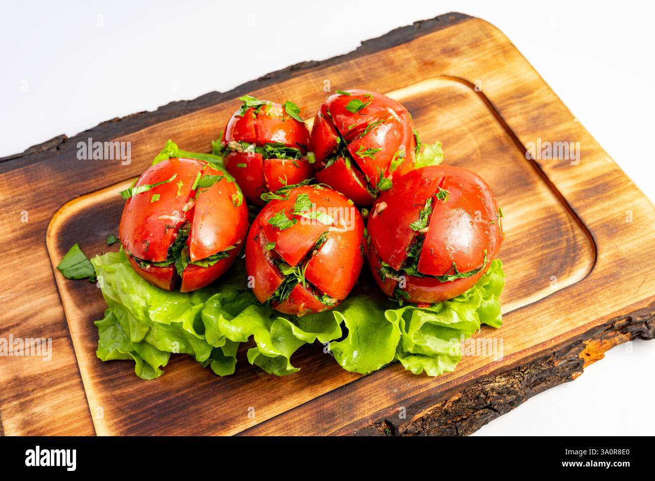 Des tomates rouges fraîches remplies d'herbes parfumées sont disposées sur un lit de laitue croustillante, mettant en valeur des couleurs vives et une présentation saine. Parfait fo Banque D'Images