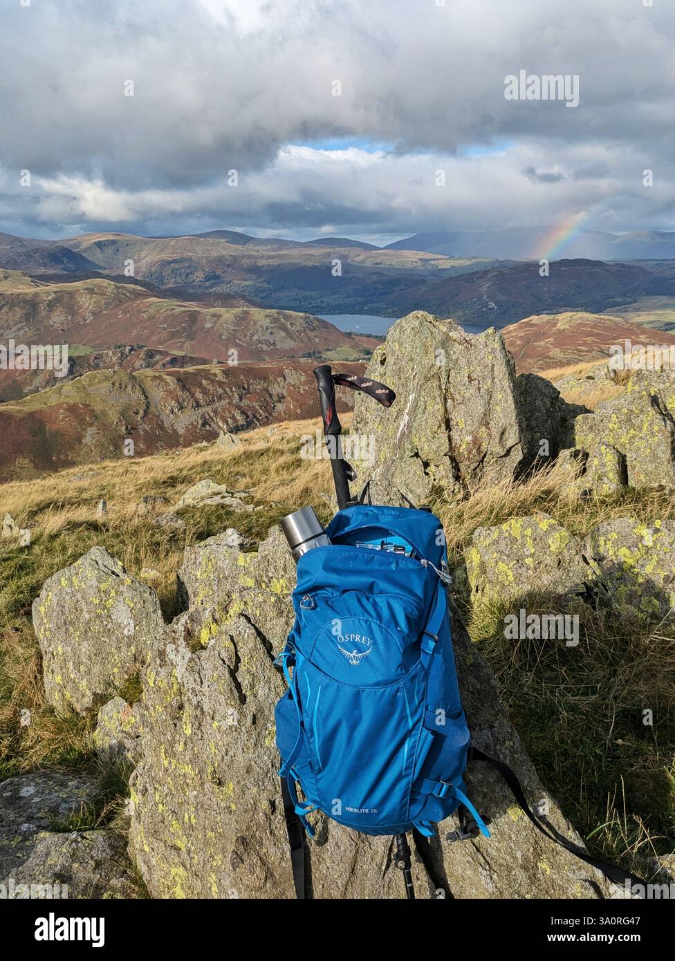 Un sac à dos de randonneur sur l'épaule de Loadpot Hill dans le Lake District anglais, avec un arc-en-ciel, Ullswater et la chaîne Helvellyn au loin. - Image de stock capturée avec un smartphone