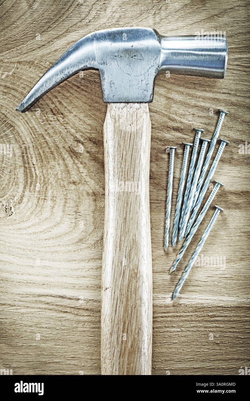 Clous métalliques de marteau de griffe sur le concept de construction de panneaux en bois Banque D'Images