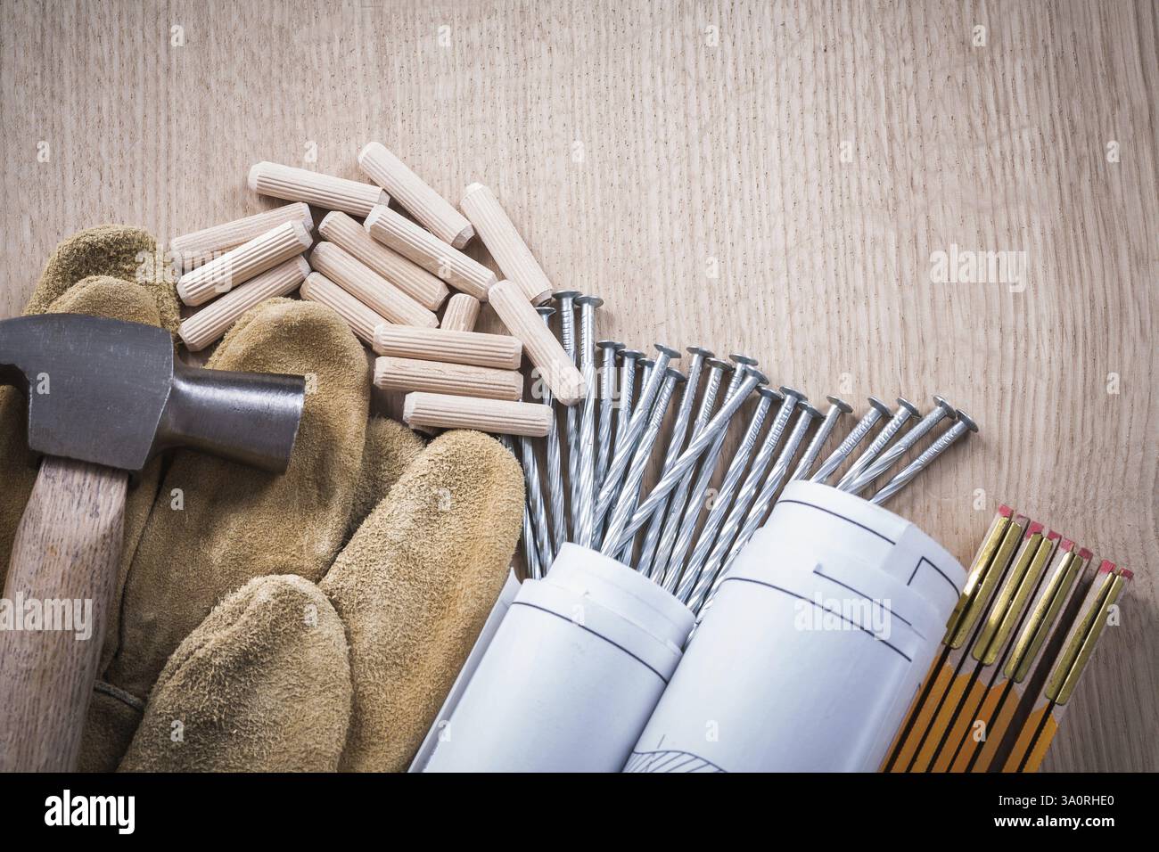 Collection de chevilles de compteur en bois dessins de construction griffe marteau gants de sécurité en cuir et clous en acier sur le concept de maintenance de planche de bois Banque D'Images