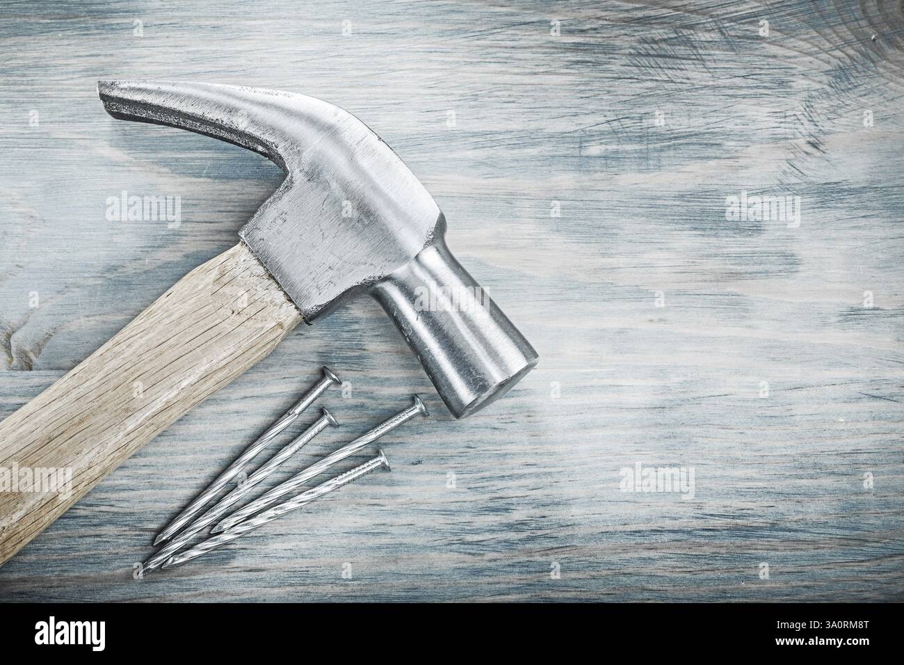 Clous métalliques de marteau de griffe sur le concept de construction de planche en bois Banque D'Images