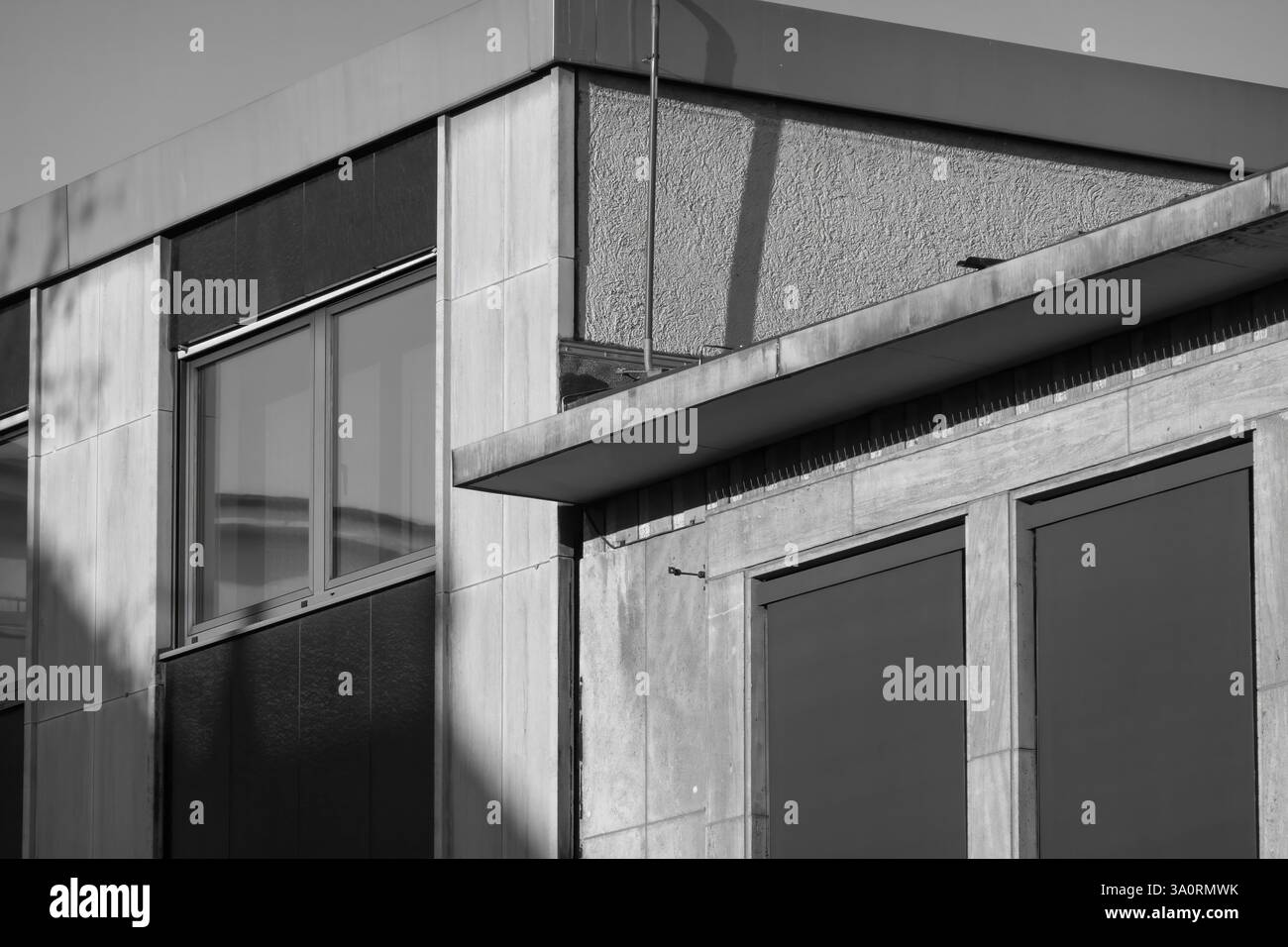 La lumière du soleil projette des ombres sur un bâtiment en béton aux formes géométriques, mettant en valeur le style architectural moderniste en monochrome Banque D'Images