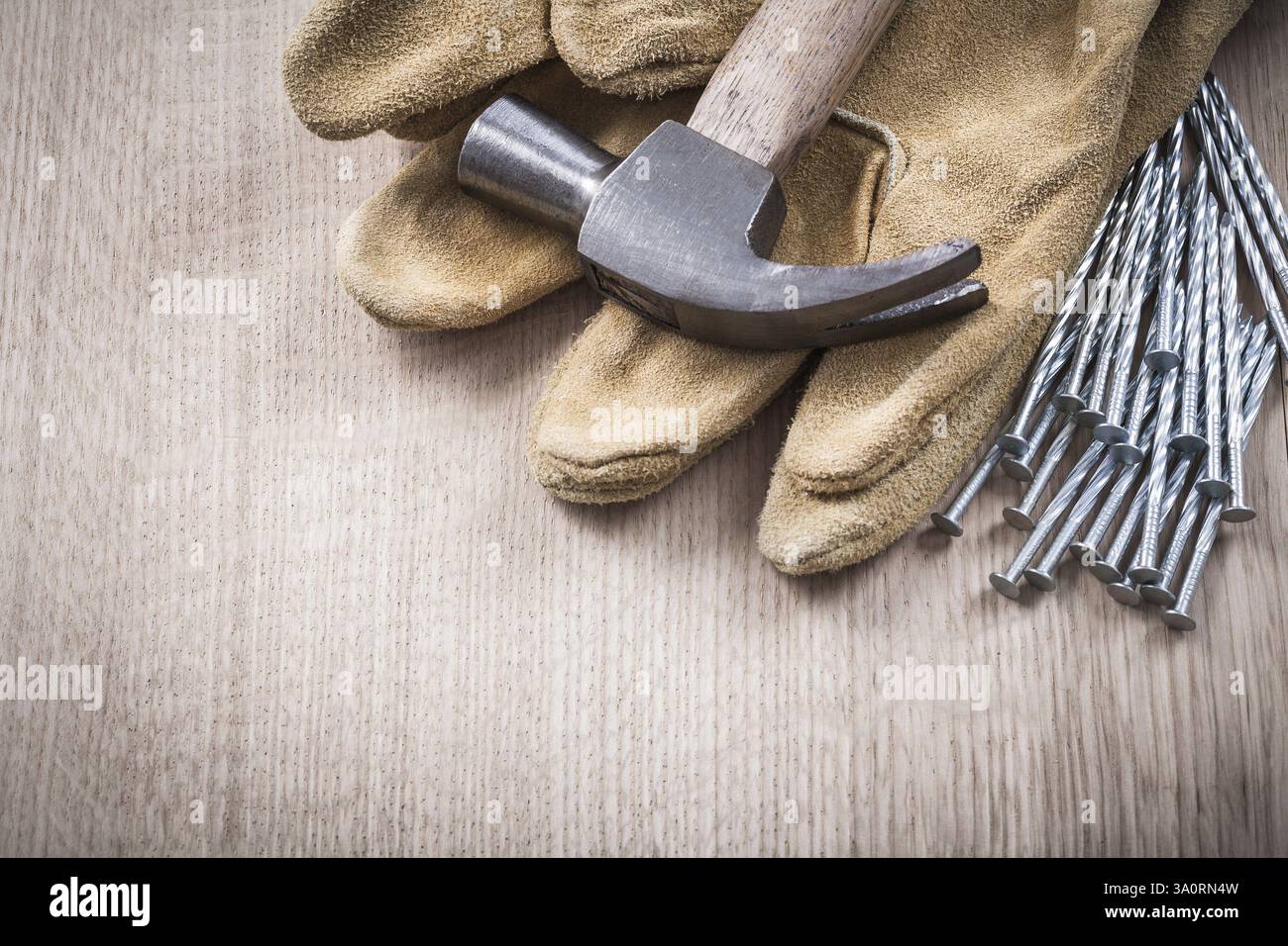 Gants de protection en cuir de marteau à griffes et tas de clous en métal sur planche de bois Close Up version concept de construction Banque D'Images