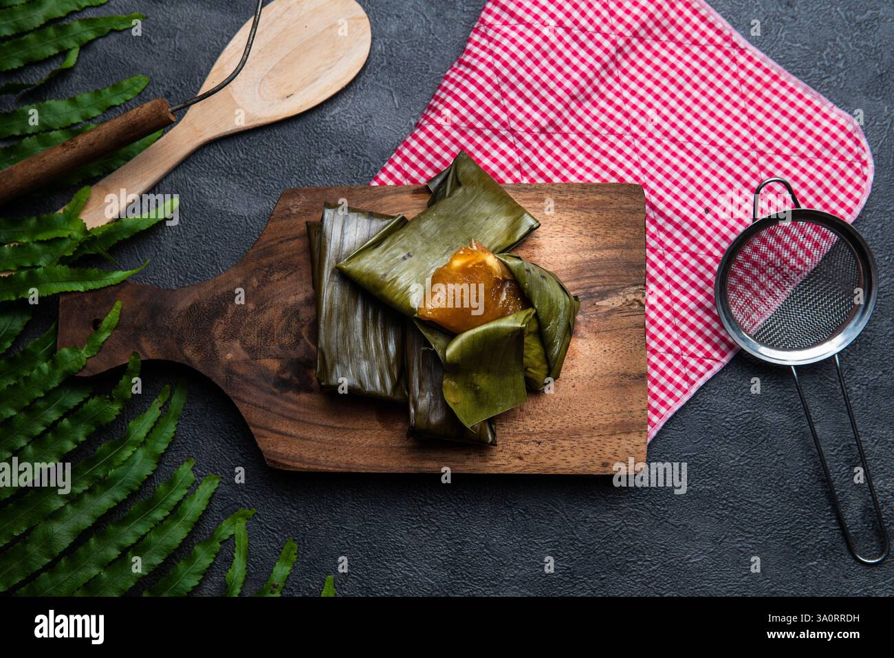 Lemet Cassava gâteau enveloppé dans une feuille de banane sur planche à découper en bois Banque D'Images