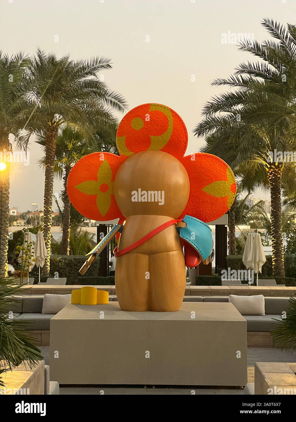 Une installation artistique visuellement frappante avec une figure ronde et stylisée avec des motifs floraux, sur fond de palmiers et de bâtiments modernes Banque D'Images
