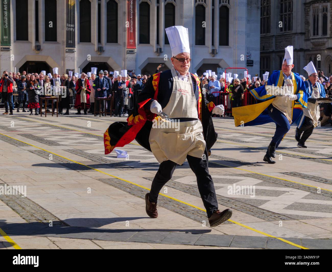 04 mars 2025, Inter-Livery Pancake Day Race à Guildhall Yard, Londres, Royaume-Uni – les membres de Livery Company, vêtus de regalia complètes, courent en retournant des crêpes dans une poêle lourde. Cette tradition annuelle Shrove Tuesday recueille des fonds pour la charité, mêlant histoire, compétition et esprit communautaire. Banque D'Images