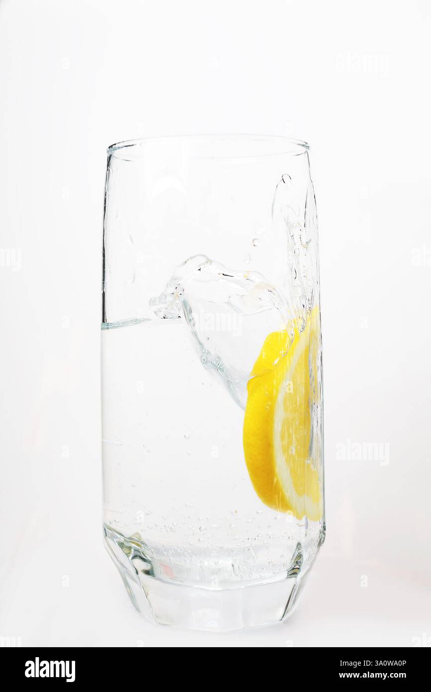une tranche de citron tombe dans un verre de soda, avec de l'eau de limonade maison Banque D'Images