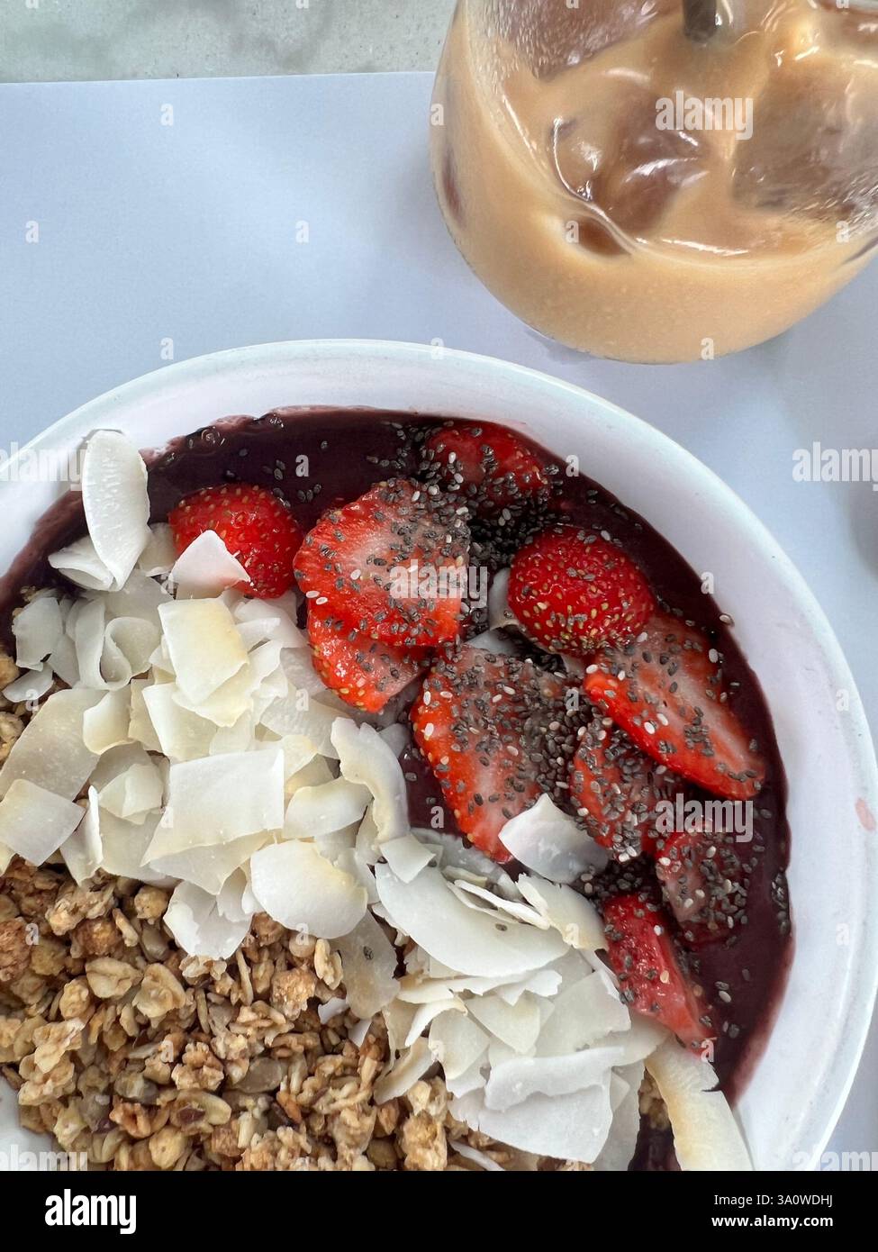 Bol Acai garni de fraises, de granola, de noix de coco et de graines de chia. Banque D'Images