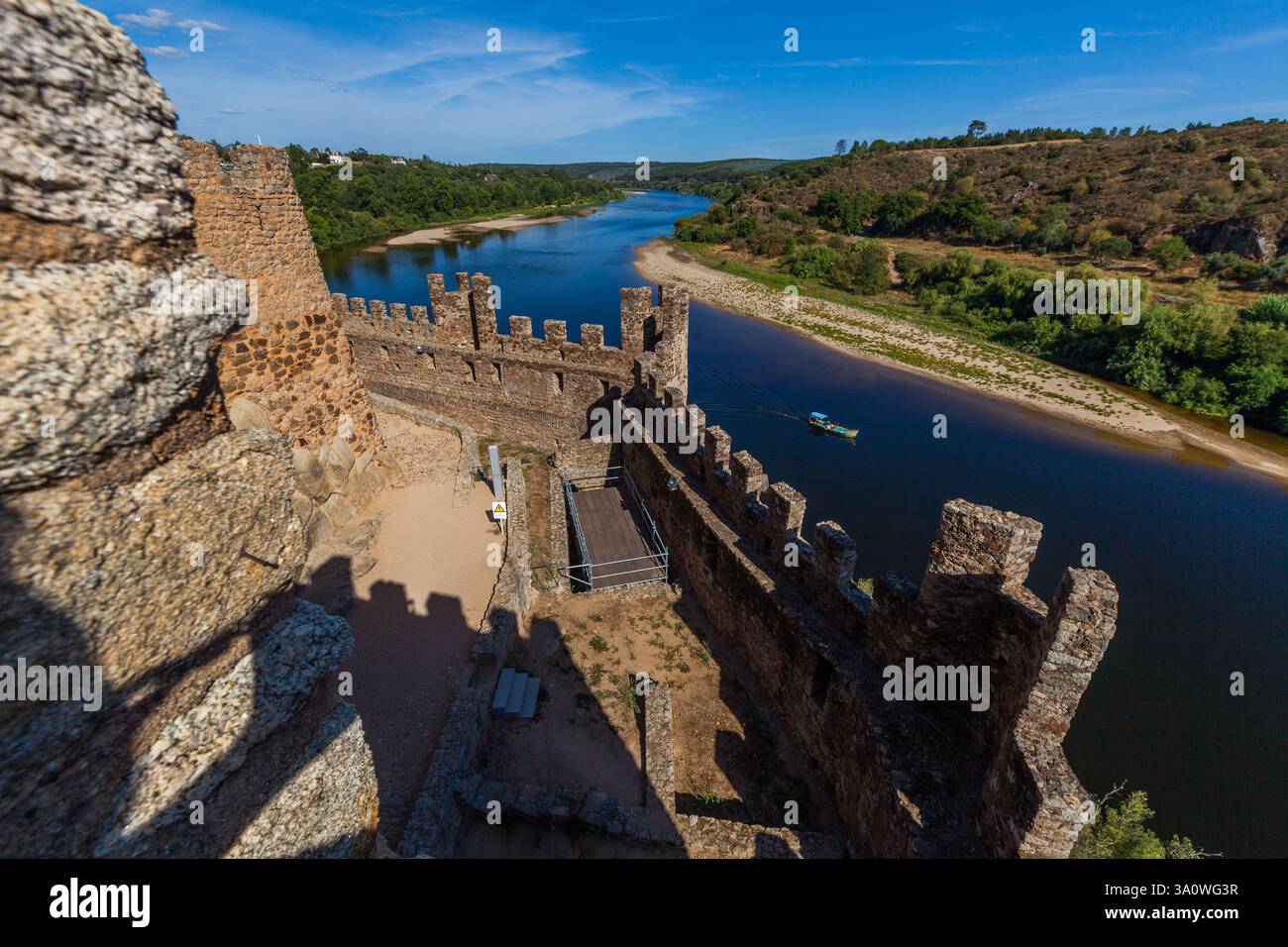 rivière tranquille encadrée par les murs de pierre brute d'une structure ancienne, probablement un château Banque D'Images