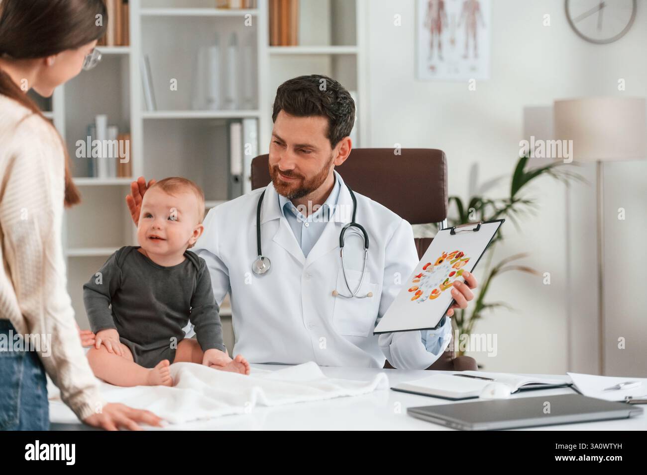 Parler d'une alimentation saine. Avec bébé et mère. Docteur en vêtements formels travaille dans le cabinet. Banque D'Images