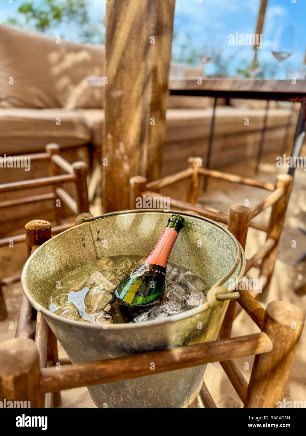 Une célébration avec champagne attendant patiemment l'arrivée de la fête, sur un patio rustique de bar de plage sur Formentera, Espagne - Image de stock capturée avec un smartphone