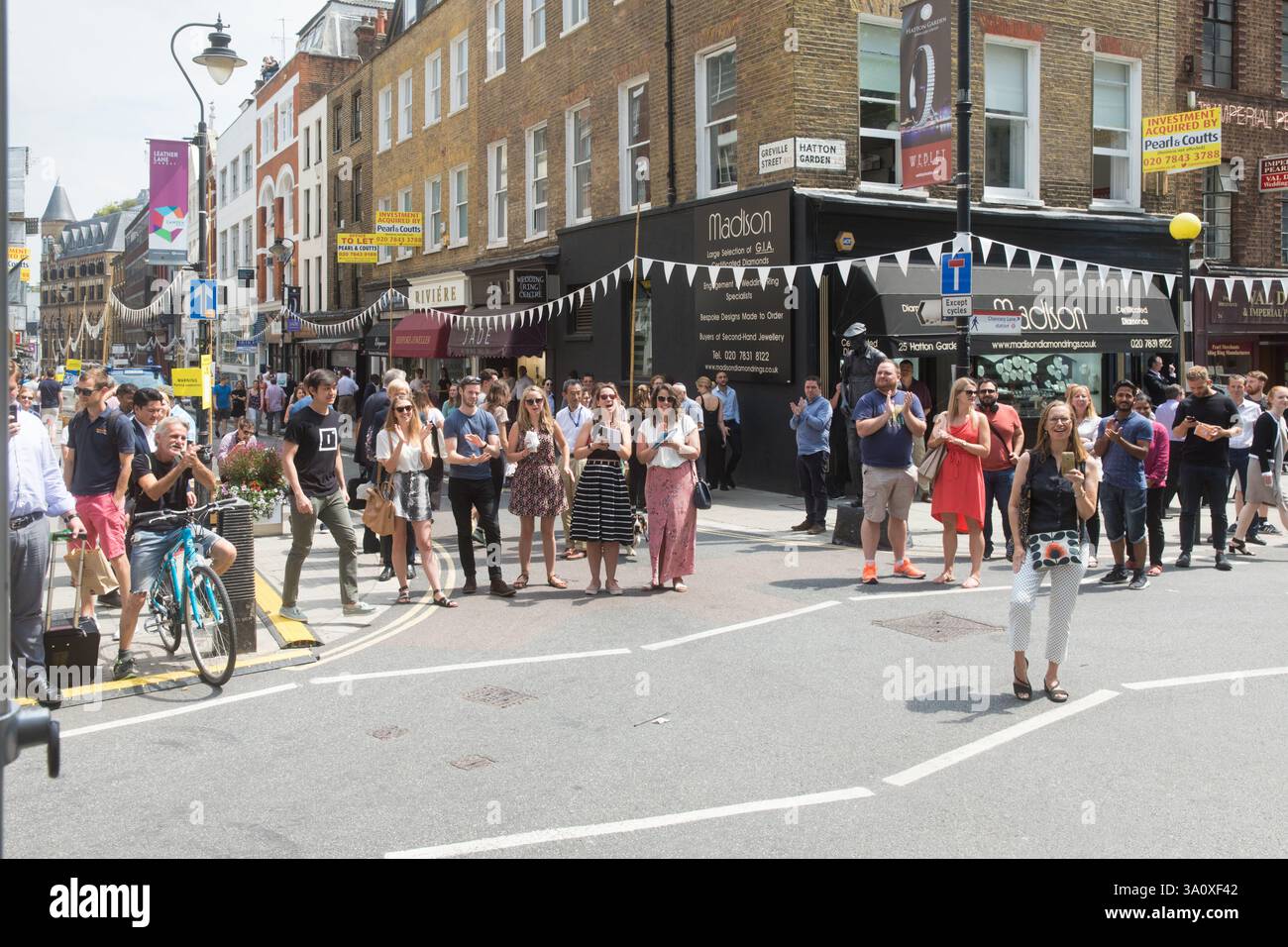 Les foules se rassemblent au 25 Hatton Garden, Londres, pour un événement de rue, probablement une célébration ou une visite. Les gens applaudissent et prennent des photos. Banque D'Images