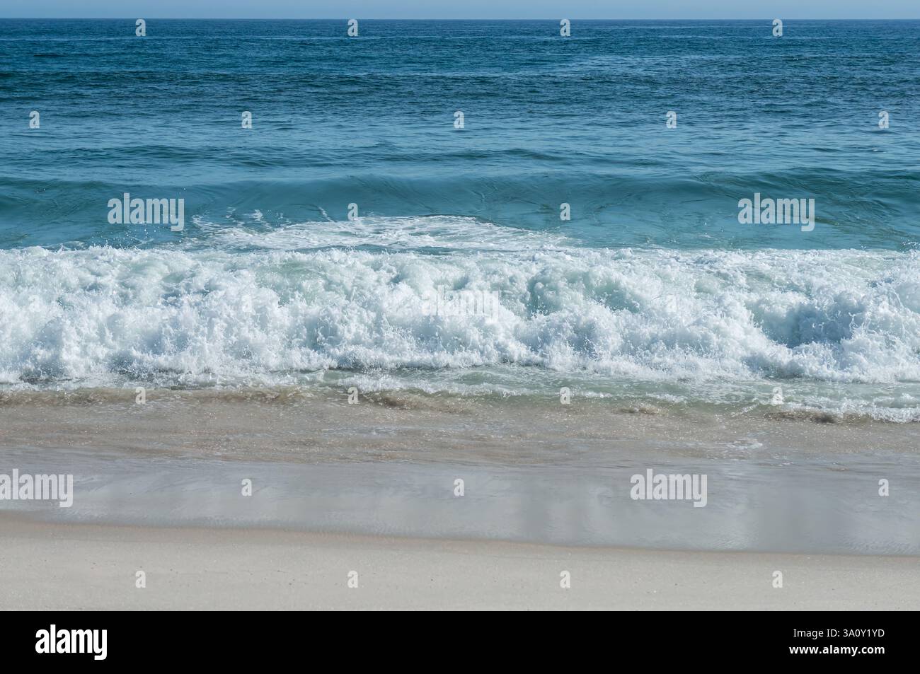 Océan Atlantique eaux bleues petites vagues se brisant sur la plage de Praia Seca sable blanc rivage sous l'après-midi d'été ensoleillé ciel bleu clair ensoleillé. Banque D'Images