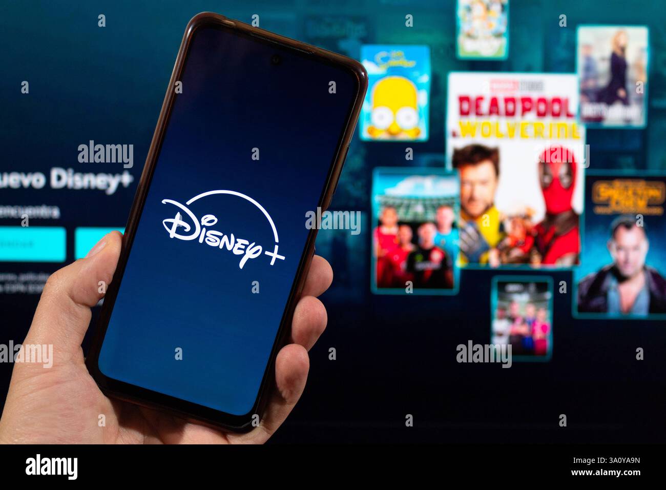 BOGOTA, COLOMBIE - MARS 05 OF 2025 Une main masculine tenant un smartphone avec sa main gauche avec le symbole Disney plus et l'interface floue en arrière-plan Banque D'Images