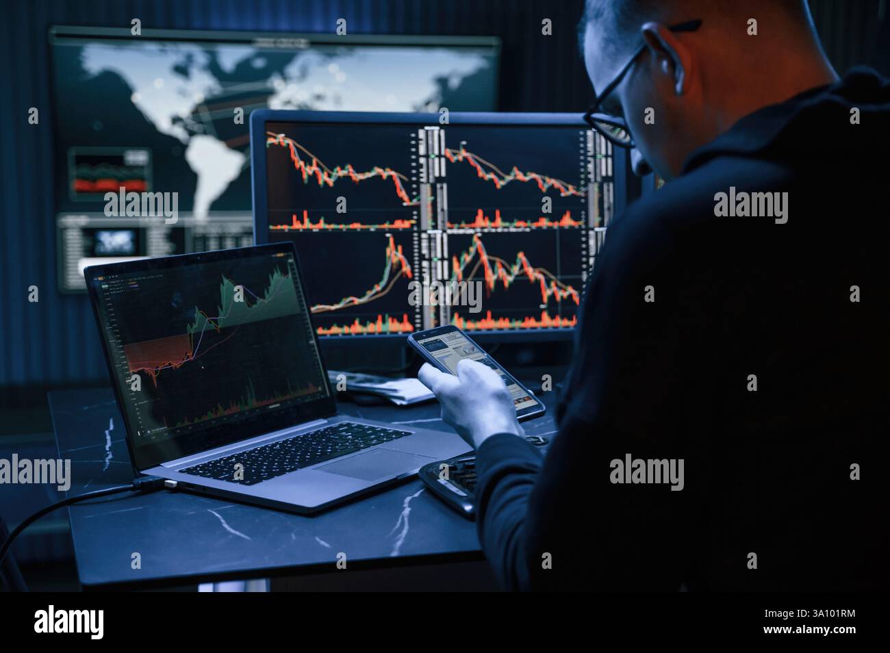 Analyste financier travaillant sur un ordinateur avec poste de travail multi-moniteurs avec des graphiques en temps réel des actions, des matières premières et des marchés des changes Banque D'Images