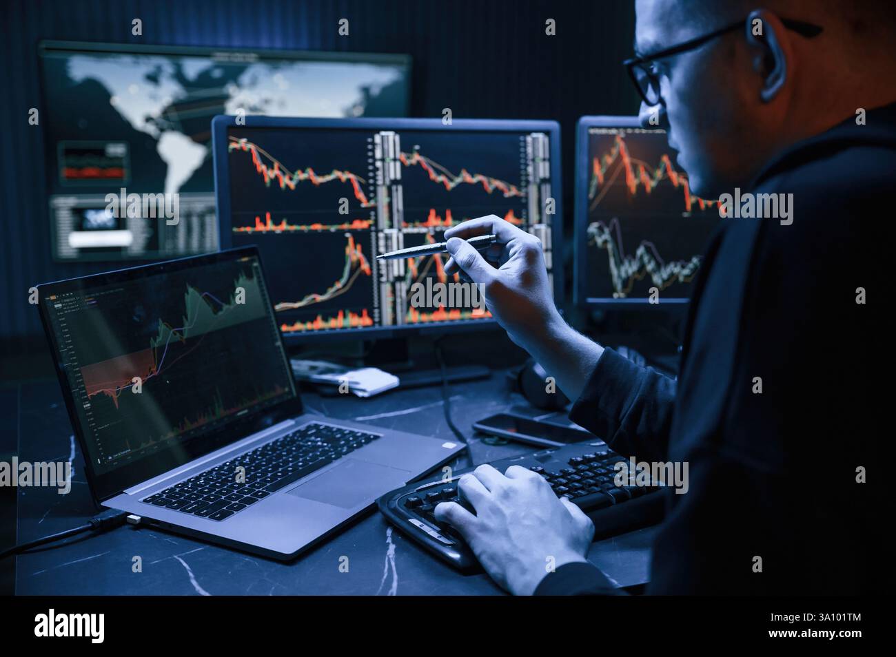 Analyste financier travaillant sur un ordinateur avec poste de travail multi-moniteurs avec des graphiques en temps réel des actions, des matières premières et des marchés des changes Banque D'Images