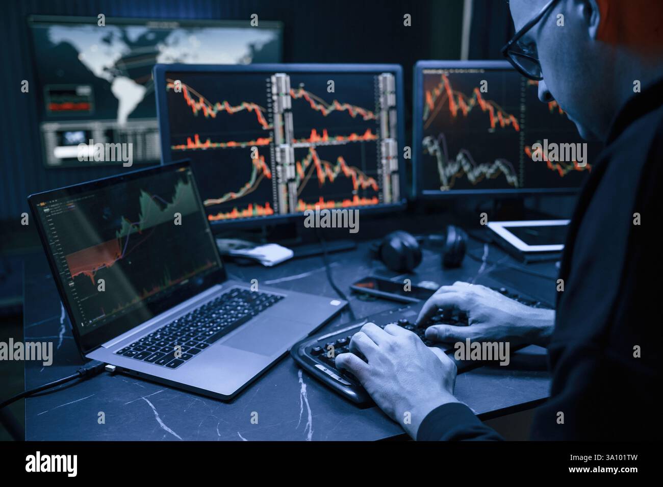 Analyste financier travaillant sur un ordinateur avec poste de travail multi-moniteurs avec des graphiques en temps réel des actions, des matières premières et des marchés des changes Banque D'Images