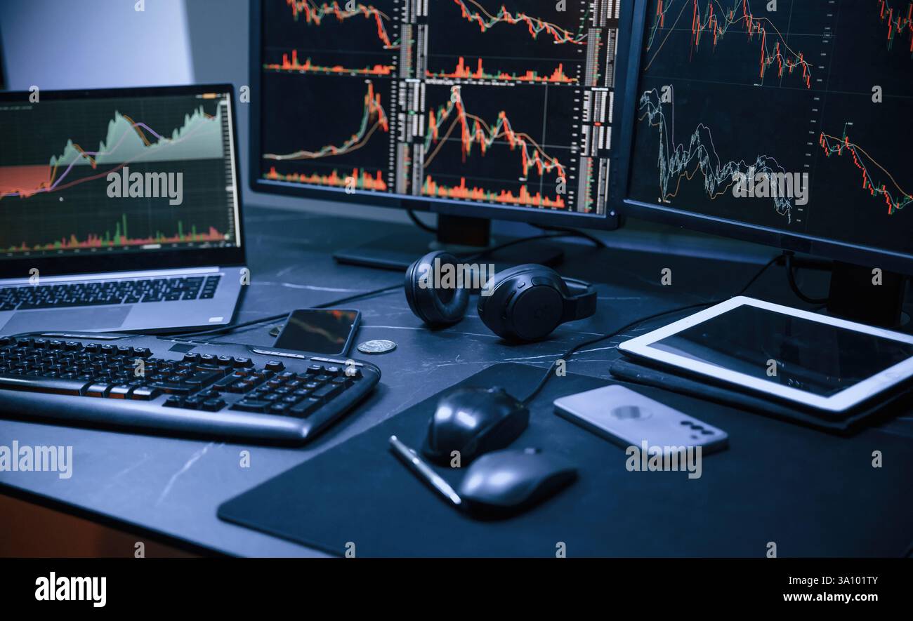 Analyste financier travaillant sur un ordinateur avec poste de travail multi-moniteurs avec des graphiques en temps réel des actions, des matières premières et des marchés des changes Banque D'Images