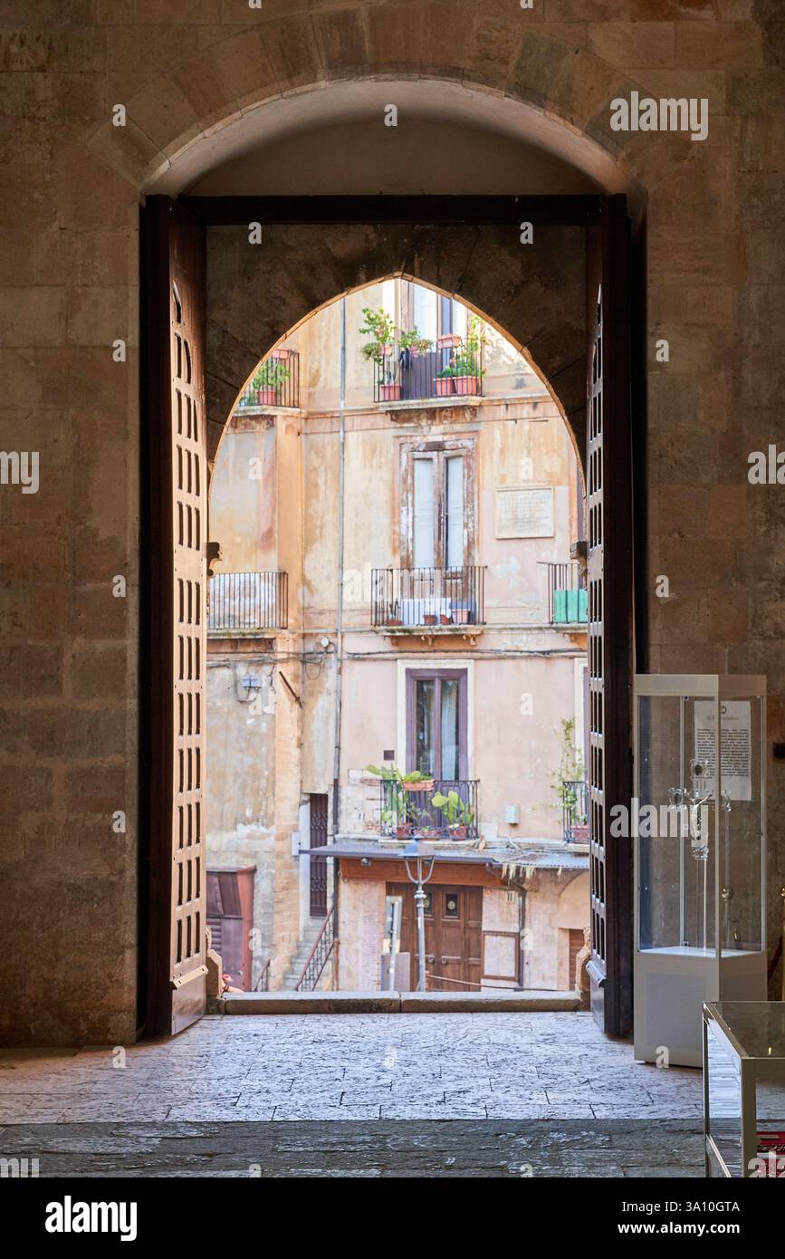 Vue à travers la porte voûtée en pierre de la cathédrale de Cosenza en regardant vers les bâtiments historiques de la place, Cosenza, Calabre, Italie. Banque D'Images
