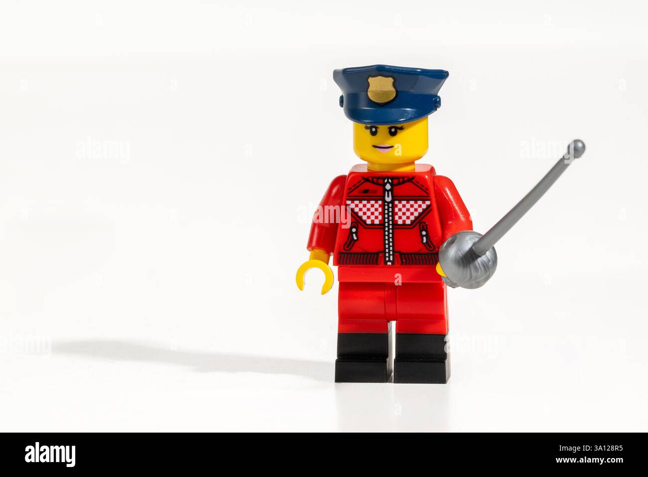 Figurine d'officier de police LEGO portant un uniforme rouge et un chapeau bleu tenant une épée sur fond blanc Banque D'Images