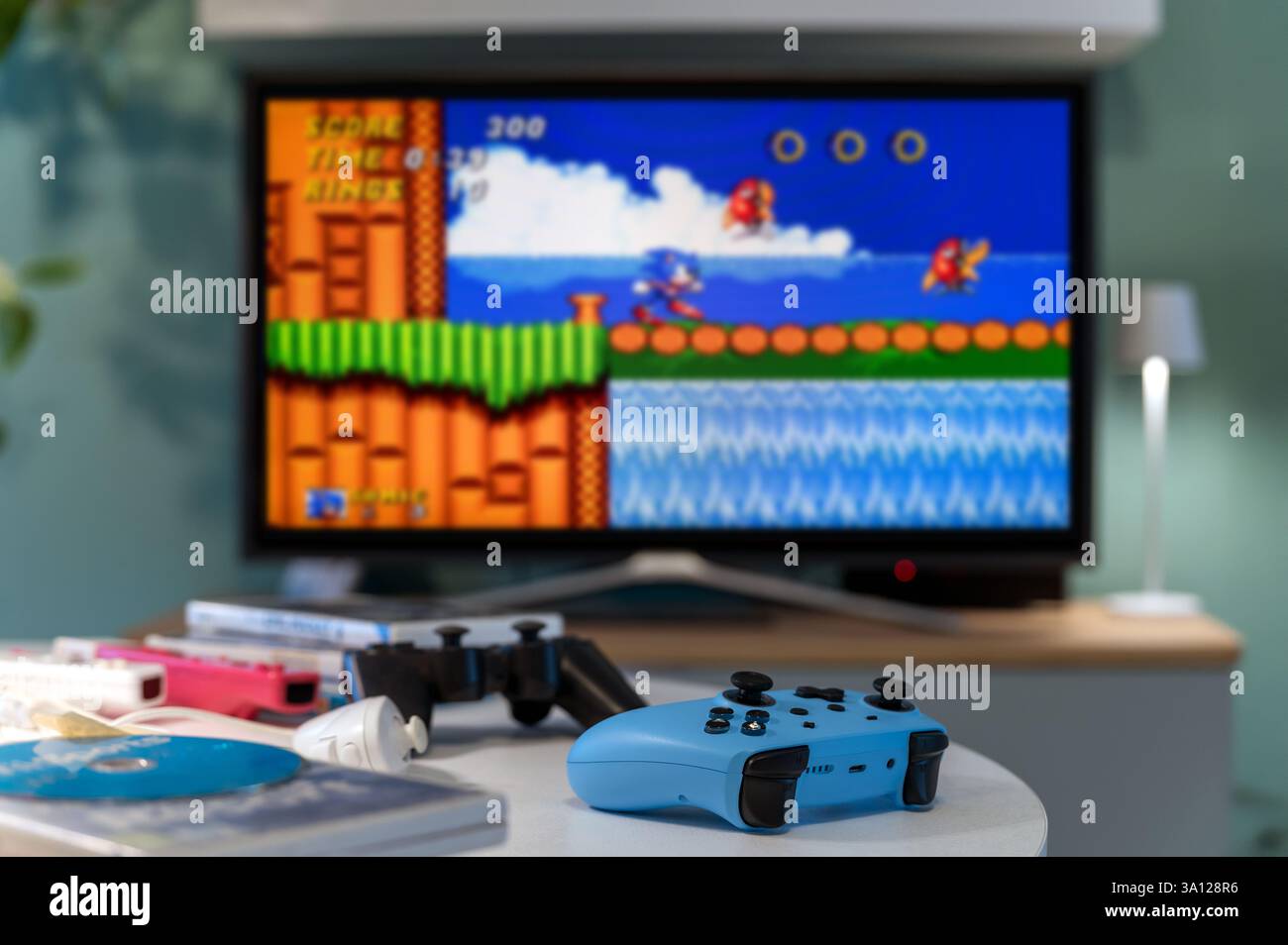 Milan, Lombardie, Italie - 24 février 2025 : Blue GamePad jouant un jeu vidéo rétro de la plateforme Sonic the Hedgehog sur un grand écran de télévision Banque D'Images