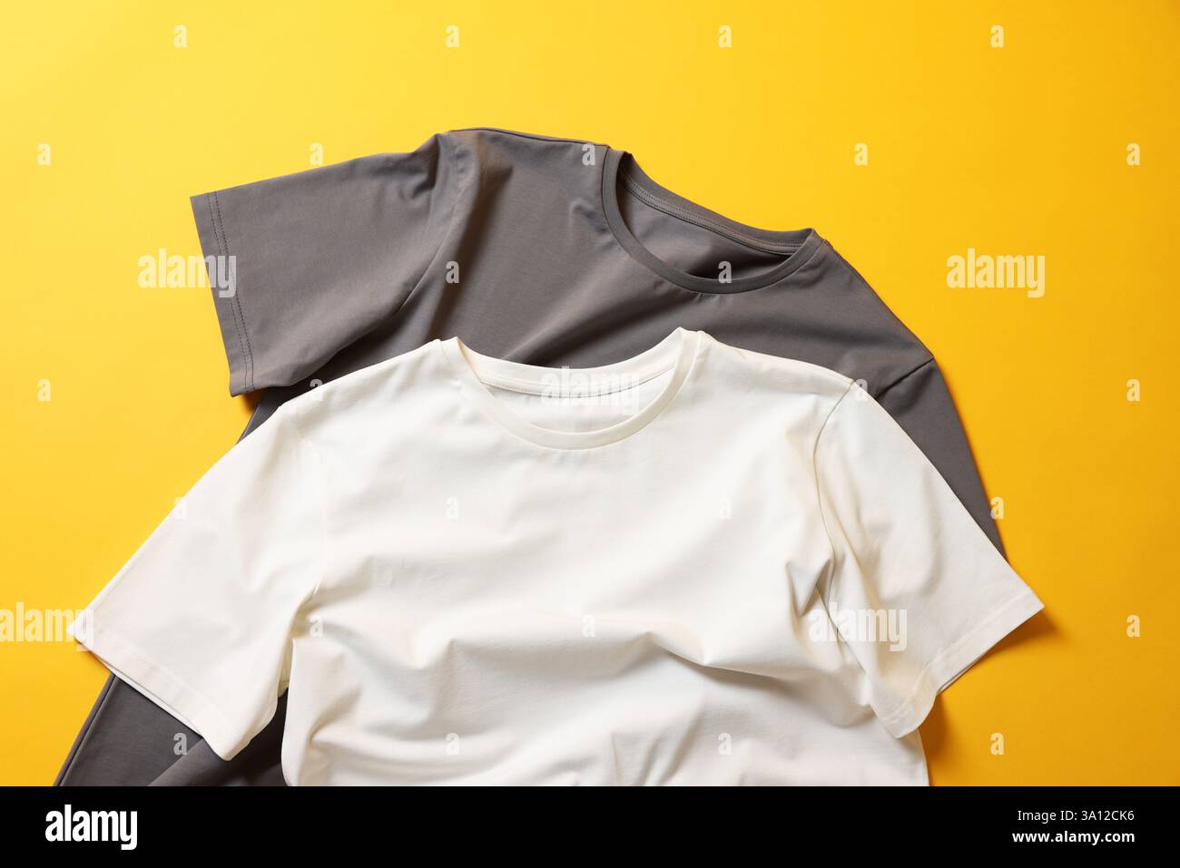 T-shirts vierges sur fond jaune, pose à plat. Maquette pour le design Banque D'Images T-shirts vierges sur fond jaune, pose à plat. Maquette pour le design Banque D'Images