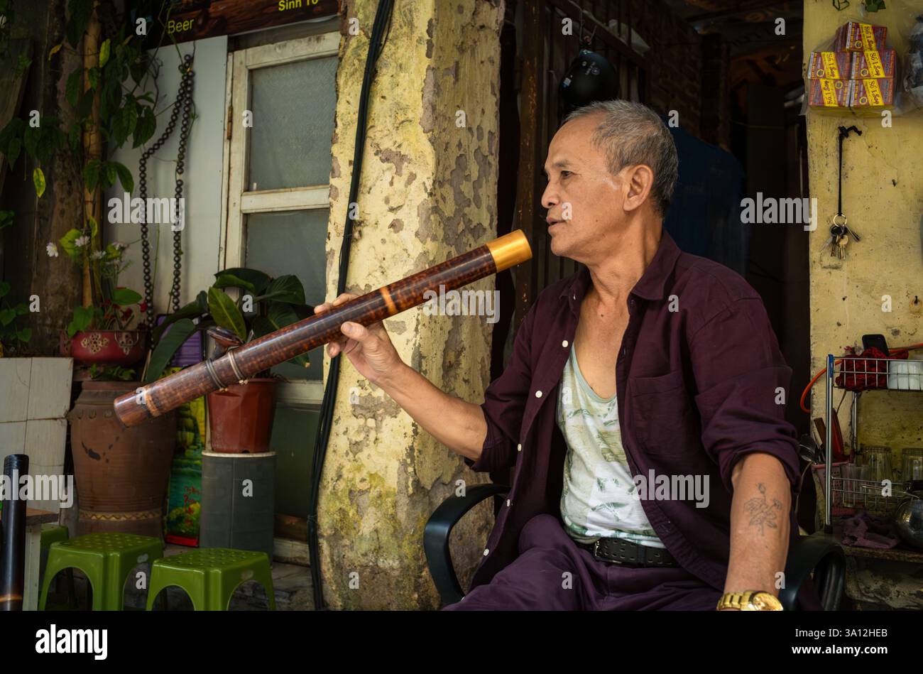 Un vendeur de rue vendant du thé vert fume du tabac fort à travers sa traditionnelle pipe à eau en bambou. Banque D'Images