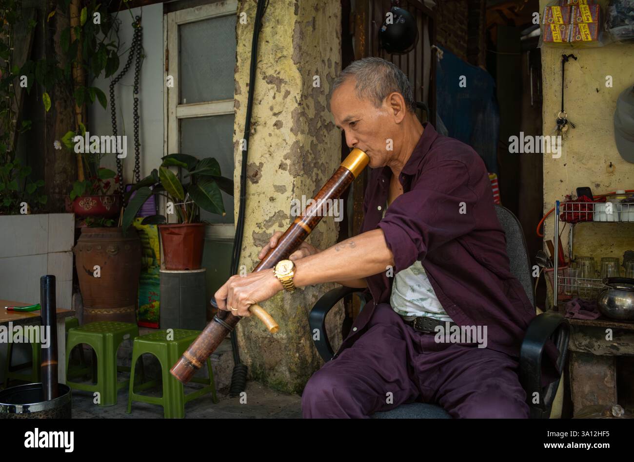 Un vendeur de rue vendant du thé vert fume du tabac fort à travers sa traditionnelle pipe à eau en bambou. Banque D'Images