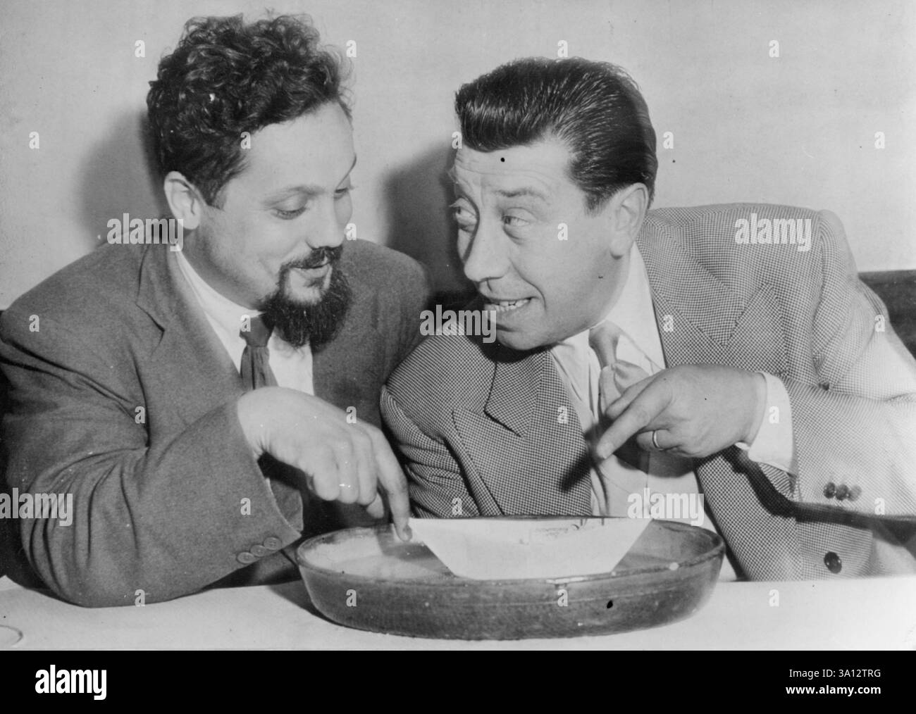 Bombard rencontre un professionnel ComedianBombard (à gauche) et Fernandel naviguent sur un bateau de papier à la fête.Dr Alain Bombard qui a émerveillé le monde en traversant l'Atlantique dans un caoutchouc dingy vivant uniquement sur les produits de l'océan et l'eau de pluie, vient de donner une fête pour lancer son nouveau livre 'le naufrage volontaire'. Lors de la fête, il a rencontré un autre homme qui a émerveillé le monde par ses actes curieux, le comédien Fernandel. 05 mai 1953. (Photo de Paul Popper). Banque D'Images