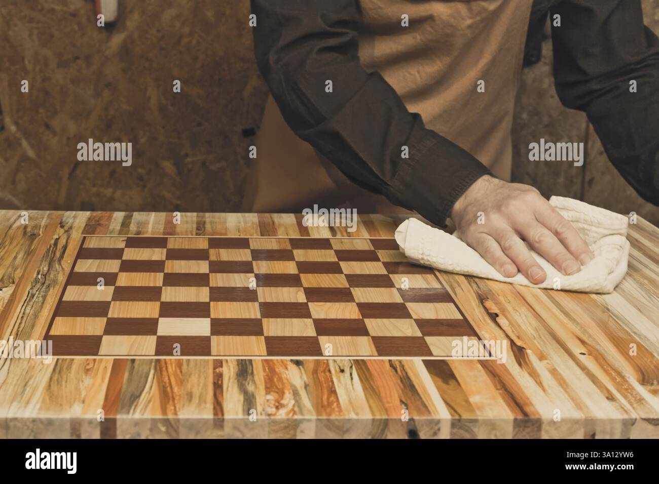 Menuisier polissant un échiquier en bois fait à la main dans son atelier Banque D'Images