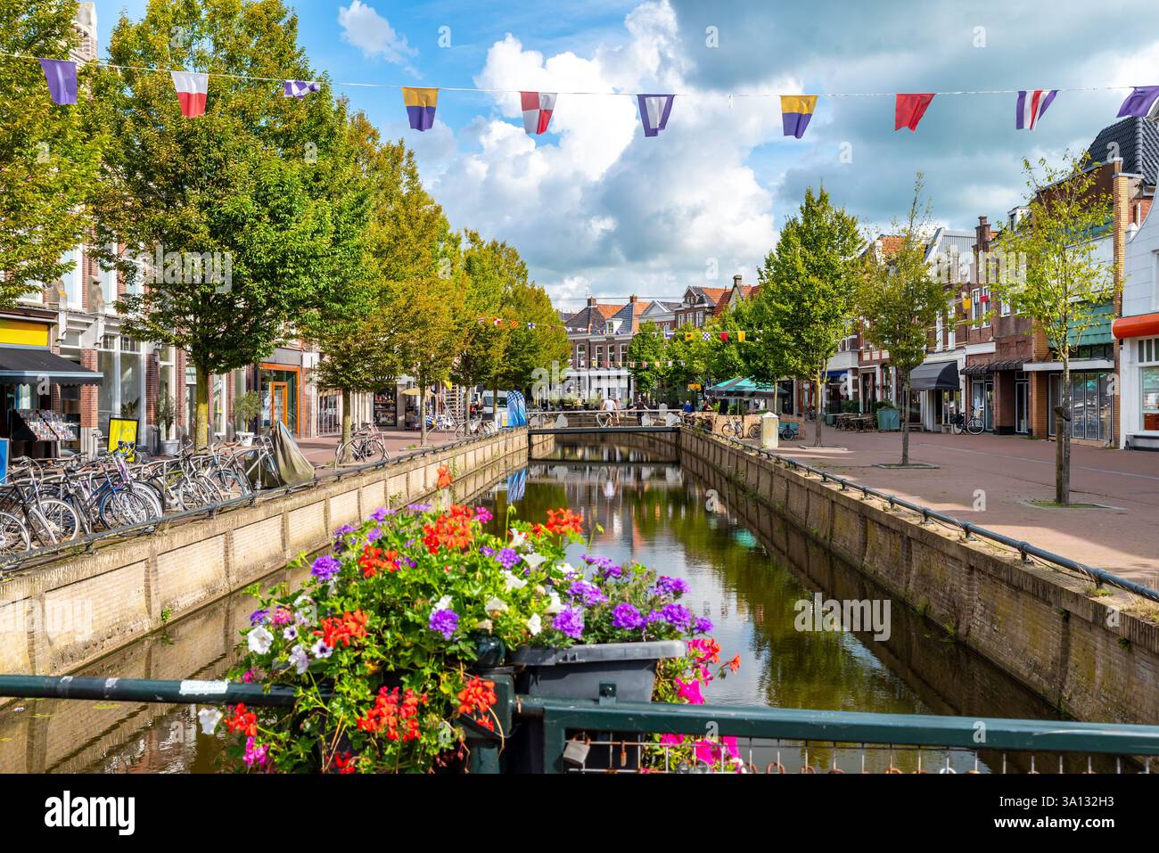 Une charmante rue canal à Sneek, aux pays-Bas, bordée d'arbres, de vélos et de bâtiments historiques. Banque D'Images