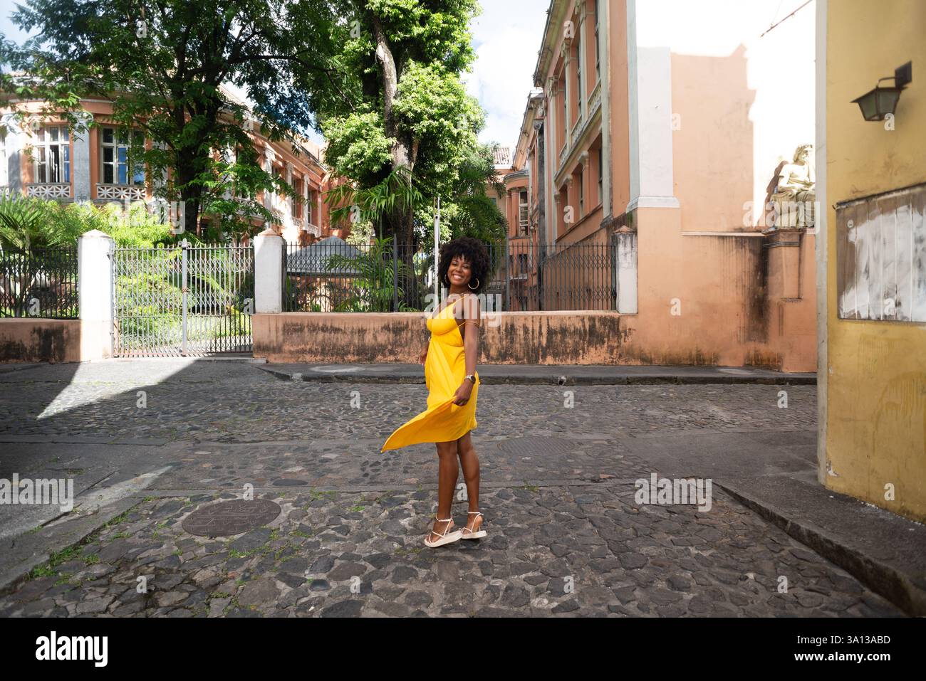 Portrait de belle femme portant une robe jaune debout sur la vieille rue pavée. Personne heureuse en voyage. Banque D'Images