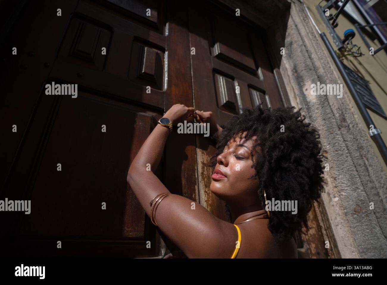 Portrait d'une belle femme portant une robe jaune debout par une vieille porte en bois brun. Concept de voyage de personne heureuse. Banque D'Images