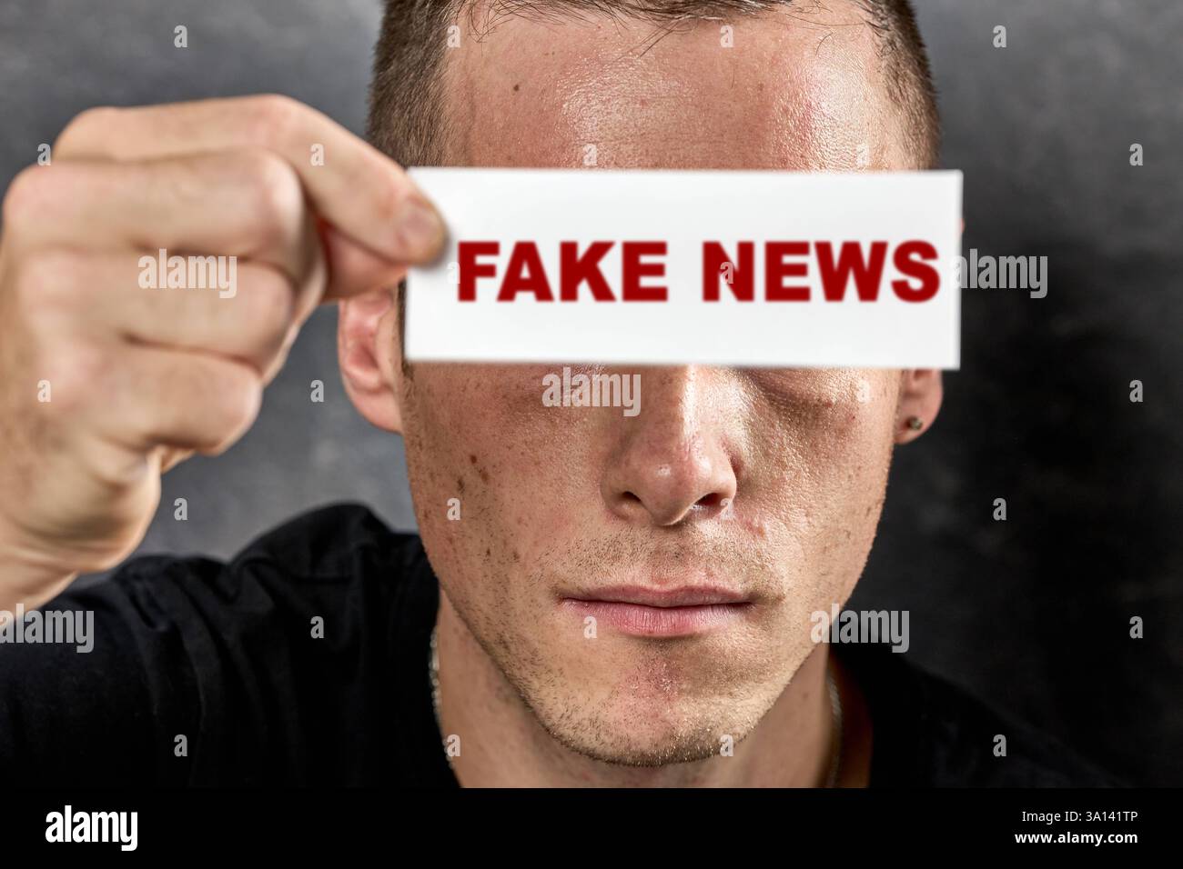 Allemagne - 6 mars 2025 : PHOTOMONTAGE, l'homme tient une pancarte avec l'inscription : FAKE NEWS, devant ses yeux. Symbole pour faux reportages, désinformation et manipulation dans les médias *** FOTOMONTAGE, Mann hält Schild mit der Aufschrift : FAKE NEWS, vor Seine Augen. Symbol für Falschmeldungen, Desinformation und manipulation in den Medien Banque D'Images