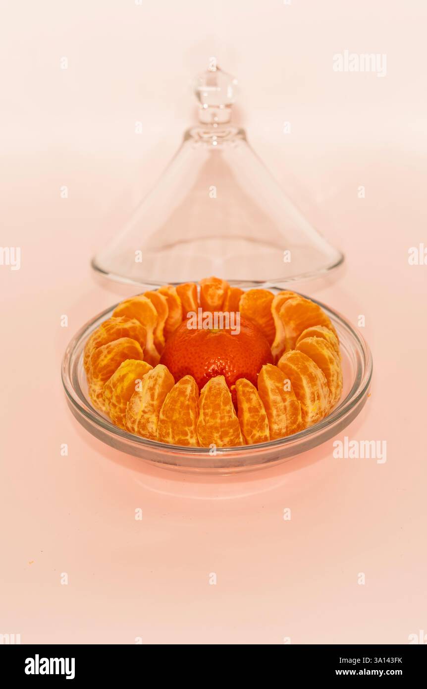 Une couronne mandarine éclatante agrémentée de segments frais dans un plat en verre, mettant en valeur l'élégance minimaliste des agrumes sous une cloche de dôme raffinée Banque D'Images Une couronne mandarine éclatante agrémentée de segments frais dans un plat en verre, mettant en valeur l'élégance minimaliste des agrumes sous une cloche de dôme raffinée Banque D'Images