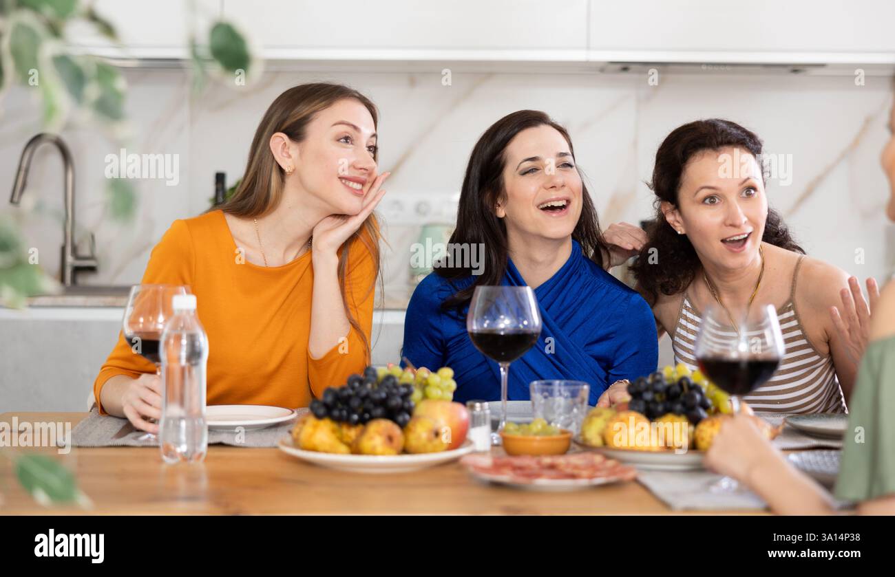 Des femmes heureuses se sont rassemblées autour d'une table festive ; participant à des discussions animées et appréciant les délices du vin Banque D'Images