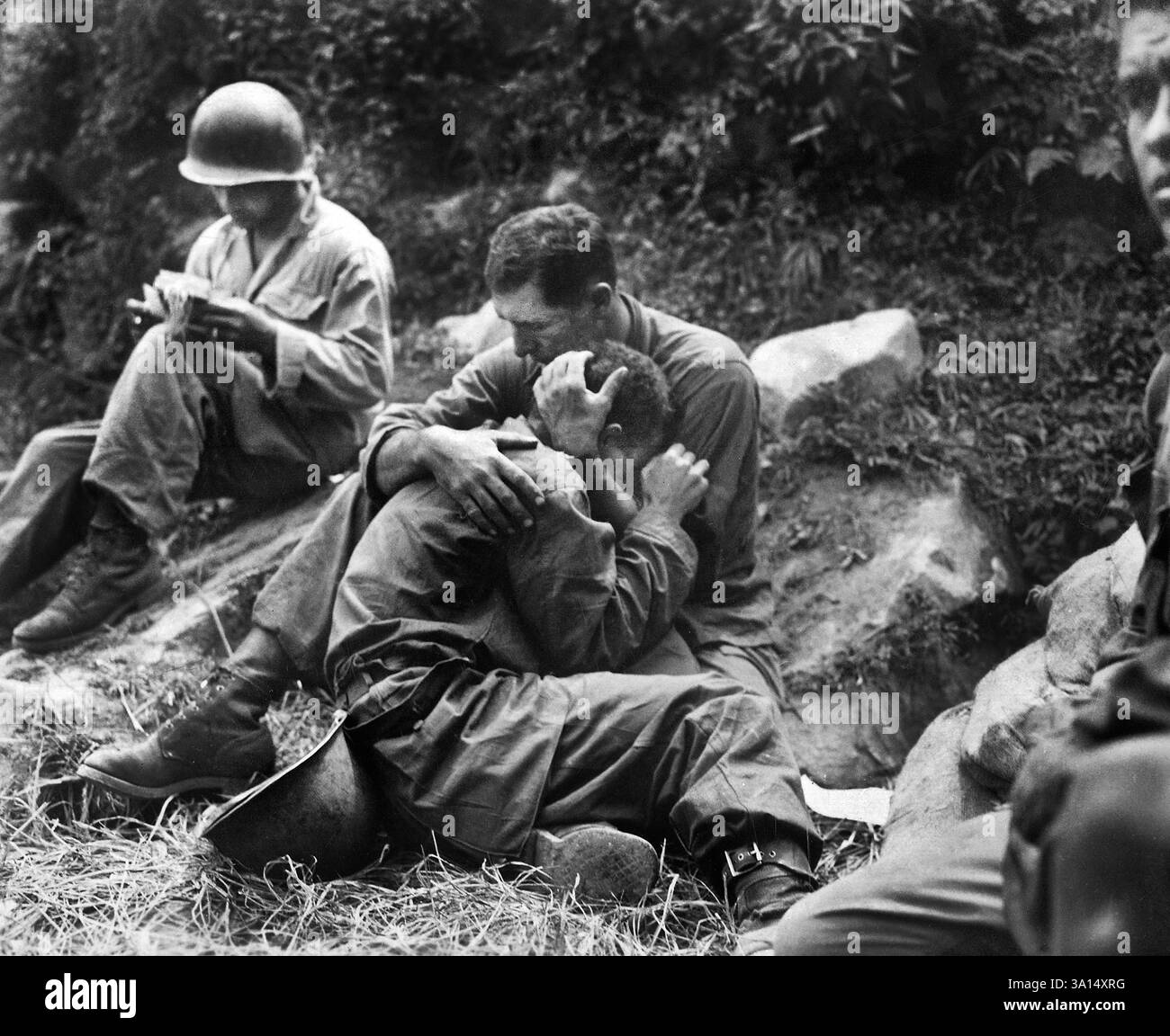 Chagrin frappa l'infanterie américaine dont le copain avait été tué au combat en étant réconforté par un autre soldat. En arrière-plan, un corpsman remplit méthodiquement des étiquettes de victimes, région de Haktong-ni, Corée, U.S. Army signal corps, 28 août 1950 Banque D'Images