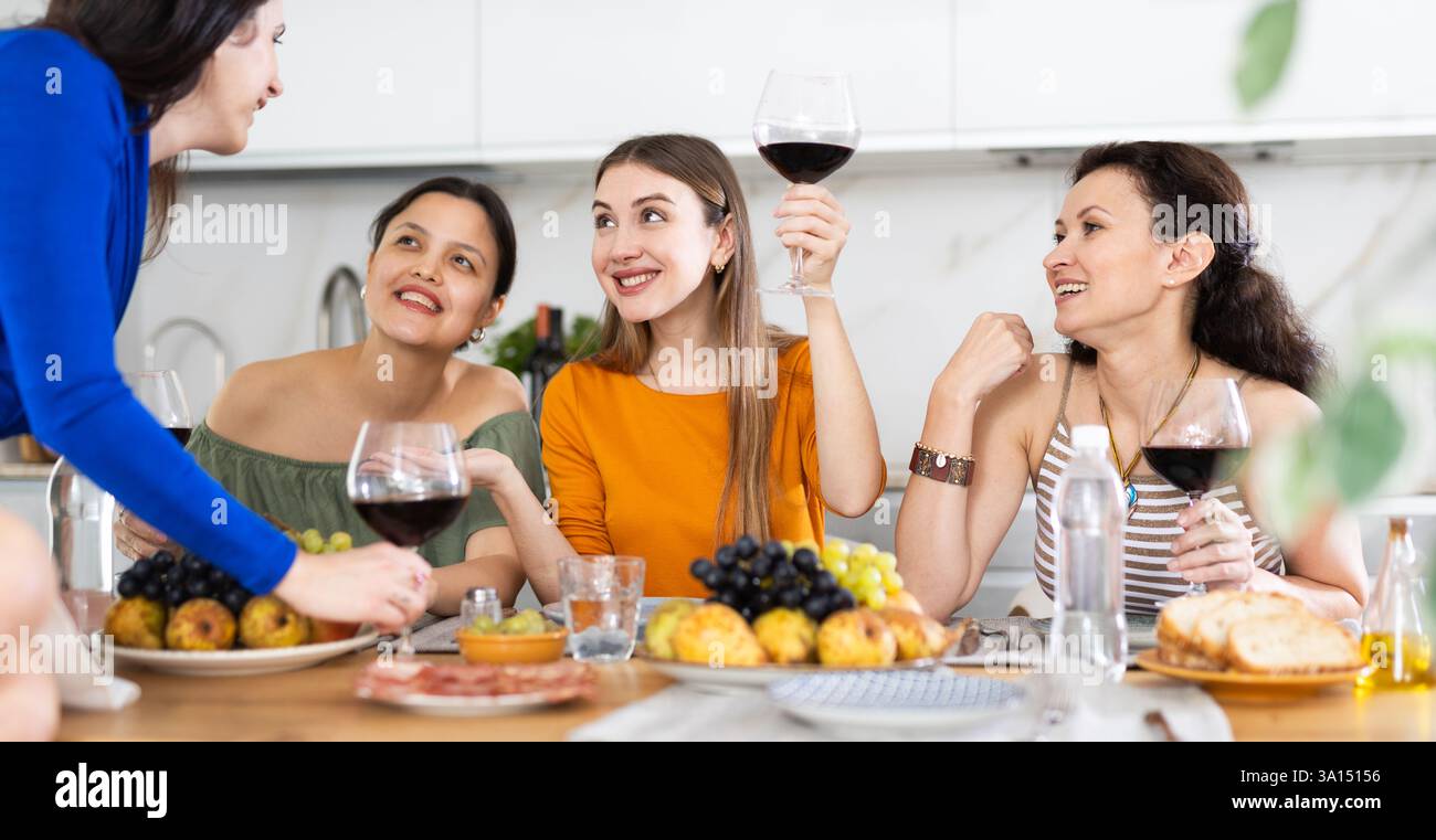 Des femmes heureuses se sont rassemblées autour d'une table festive ; participant à des discussions animées et appréciant les délices du vin Banque D'Images