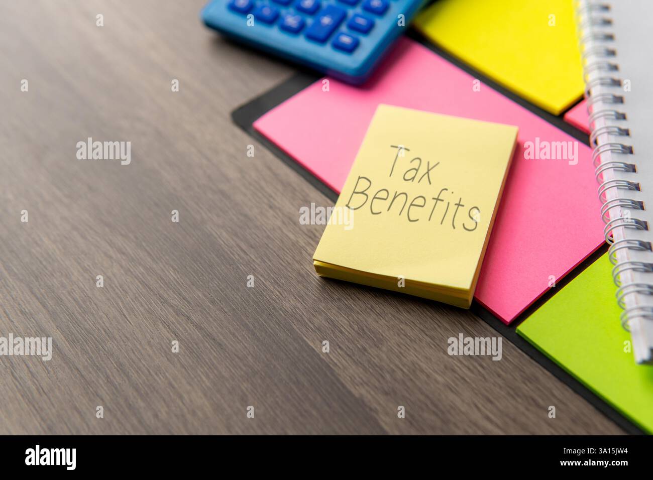 Une note autocollante jaune avec les mots « AVANTAGES FISCAUX » à côté d'une calculatrice bleue. Concept financier. Banque D'Images