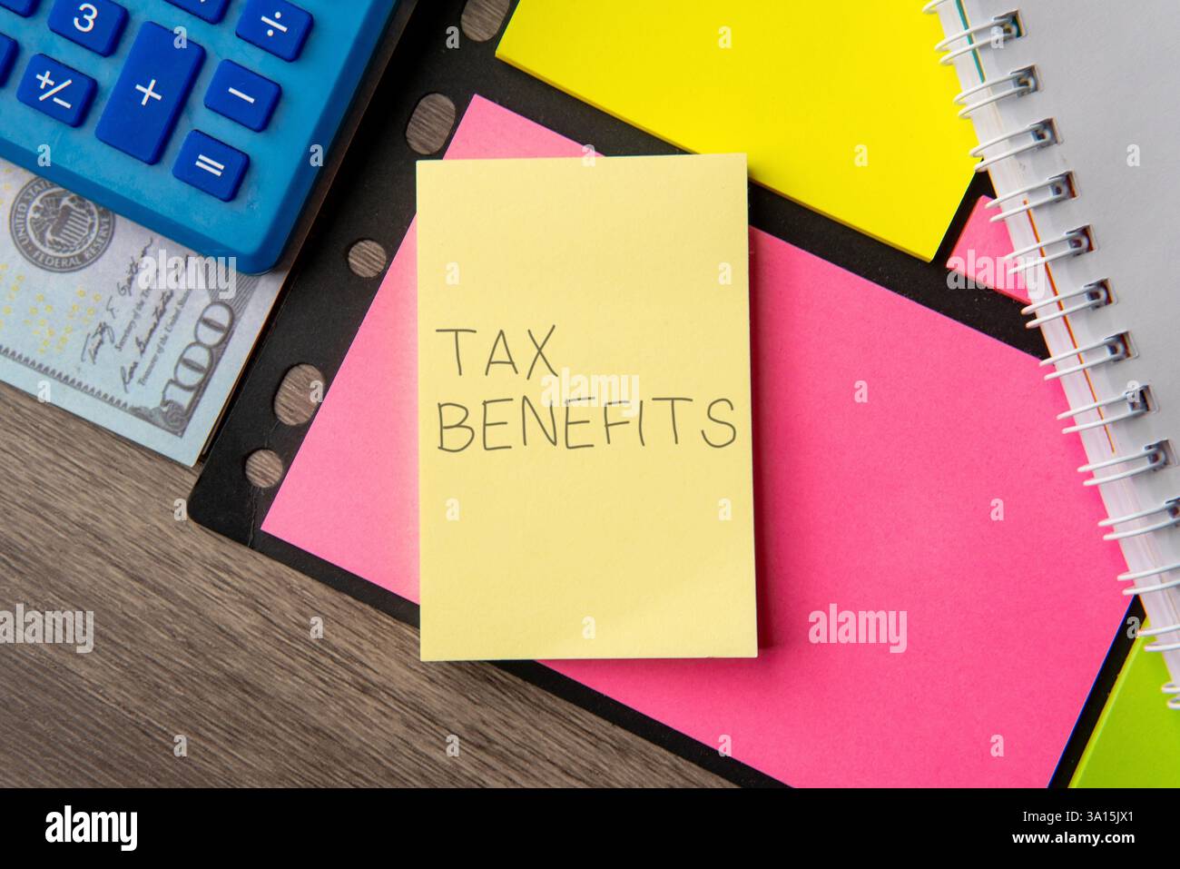 Une note autocollante jaune avec les mots « AVANTAGES FISCAUX » à côté d'une calculatrice bleue. Concept financier. Banque D'Images