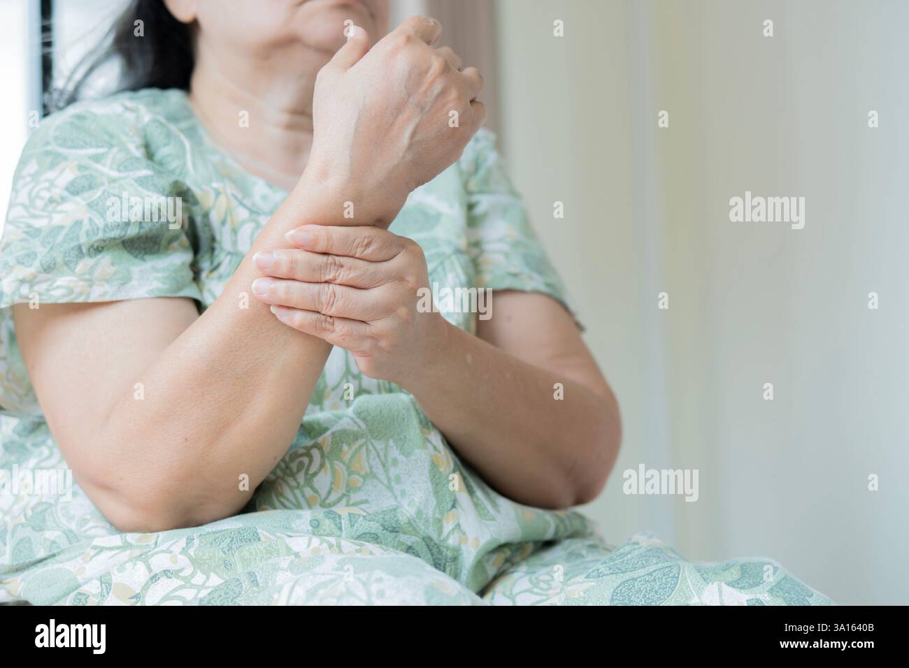 Femme asiatique mature souffrant de douleur à la main à la maison, espace pour le texte. Symptôme rhumatisme. Mise au point sélective. Banque D'Images