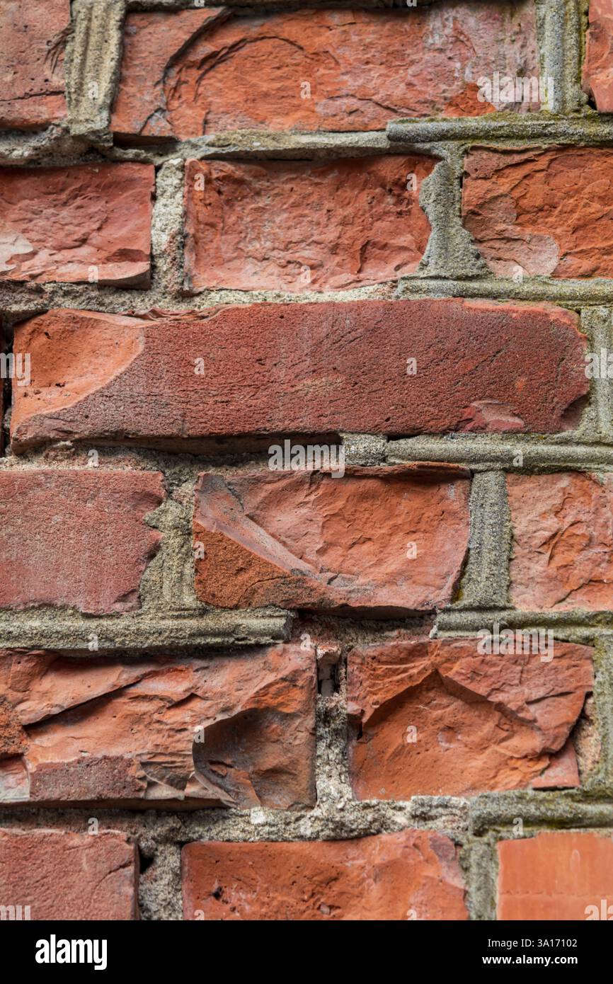 Gros plan d'un mur de briques avec quelques briques brisées et cassées, révélant des textures rugueuses, des fissures et des surfaces altérées. Idéal pour l'arrière-plan Banque D'Images