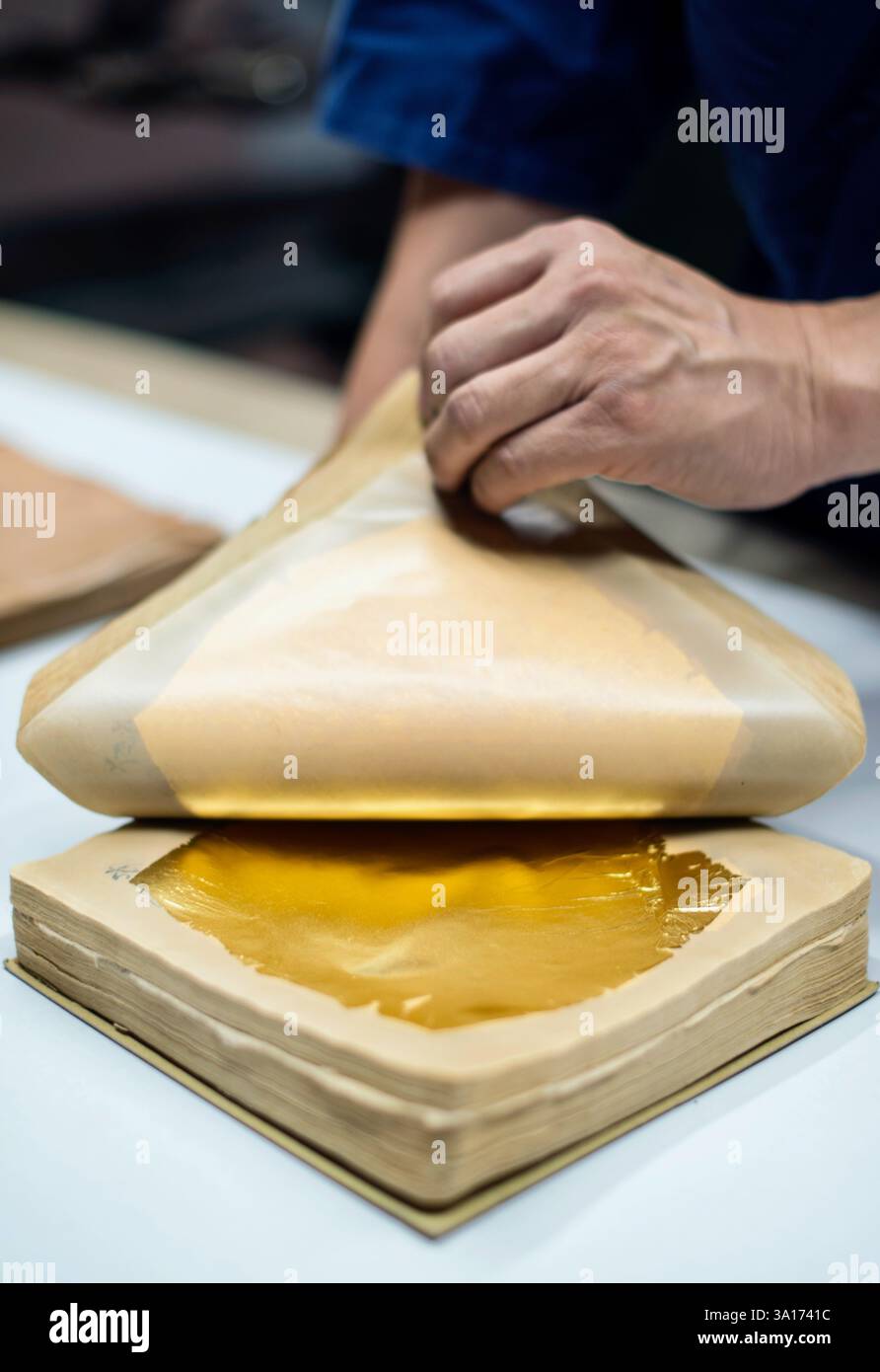 Tsutomu Yamane épluche une liasse de vieux papiers pour révéler des feuilles d'or de 0,0001 mm d'épaisseur à Hakuichi à Kanazawa, préfecture d'Ishikawa au Japon en juin Banque D'Images