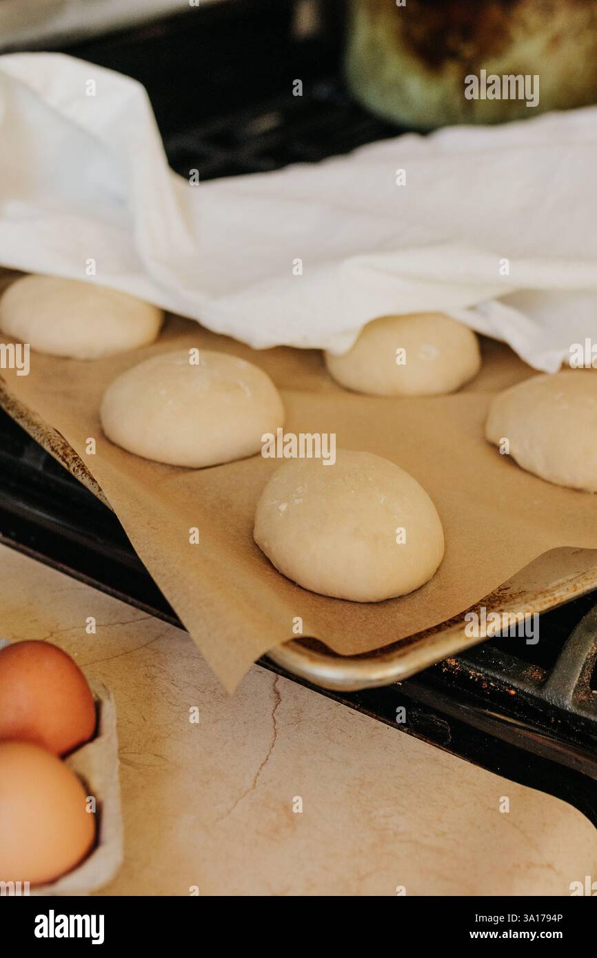 Les petits pains au levain se lèvent sur le poêle recouvert d'un torchon Banque D'Images