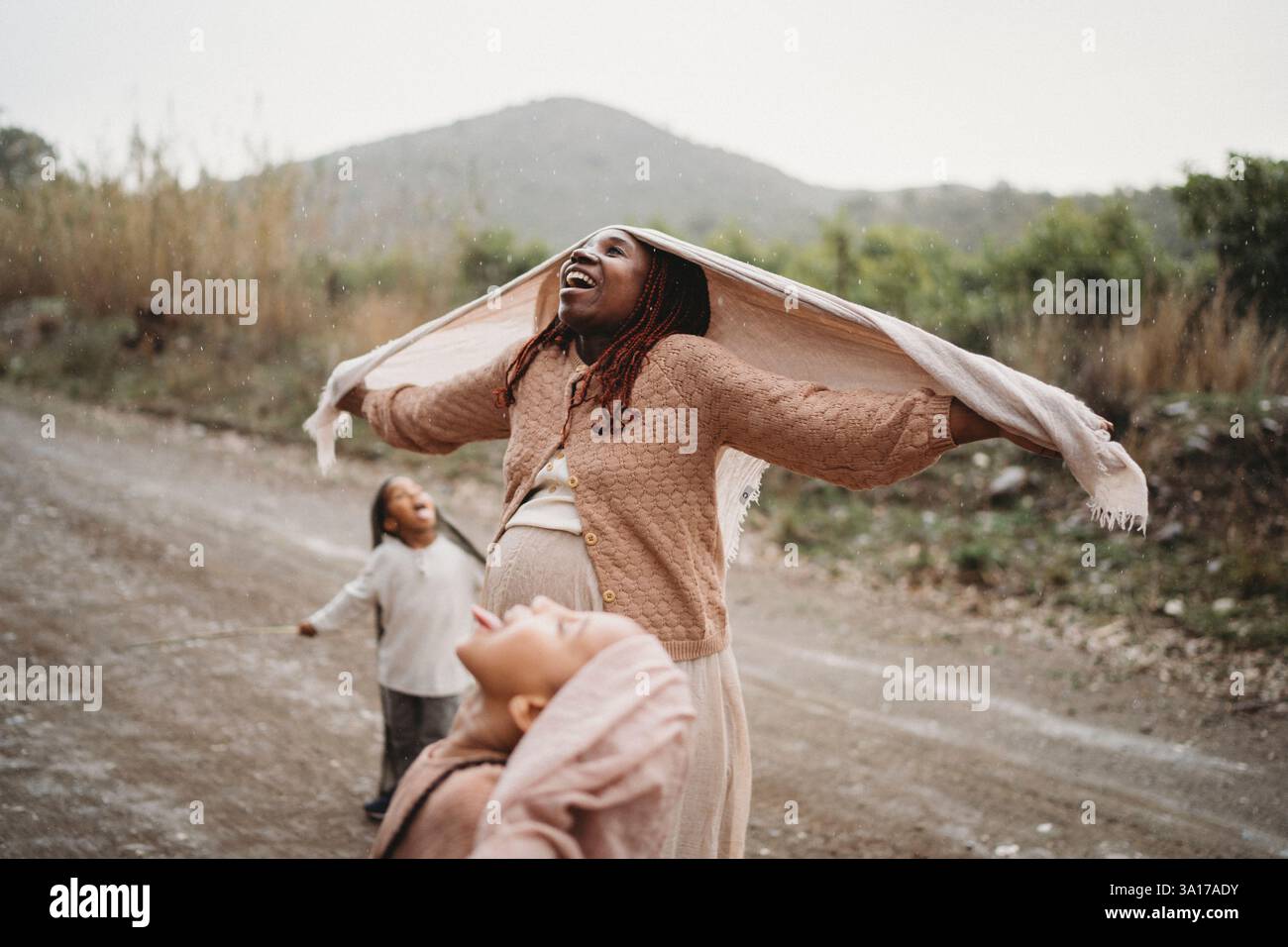 Enfants noirs dansant dans la langue de la pluie se sentant joie maman enceinte Banque D'Images