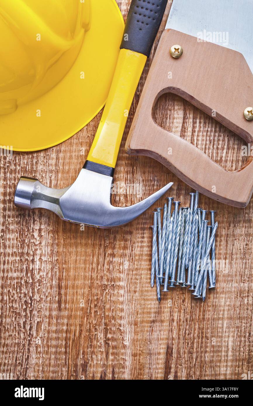 Casque scie à main marteau et clous sur la vieille planche de bois Banque D'Images