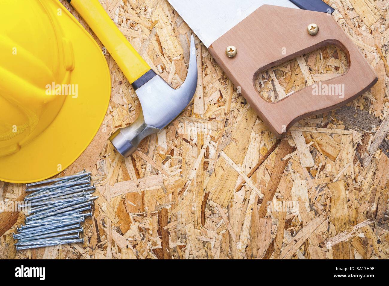 Casque scie à main marteau et clous sur vieille planche en bois version horizontale Banque D'Images