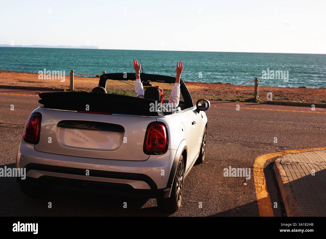 fille dans un cabriolet avec un toit ouvert voyage le long du bord de mer. Fille dans un cabriolet avec un toit ouvert en été levé ses mains, contre le Banque D'Images