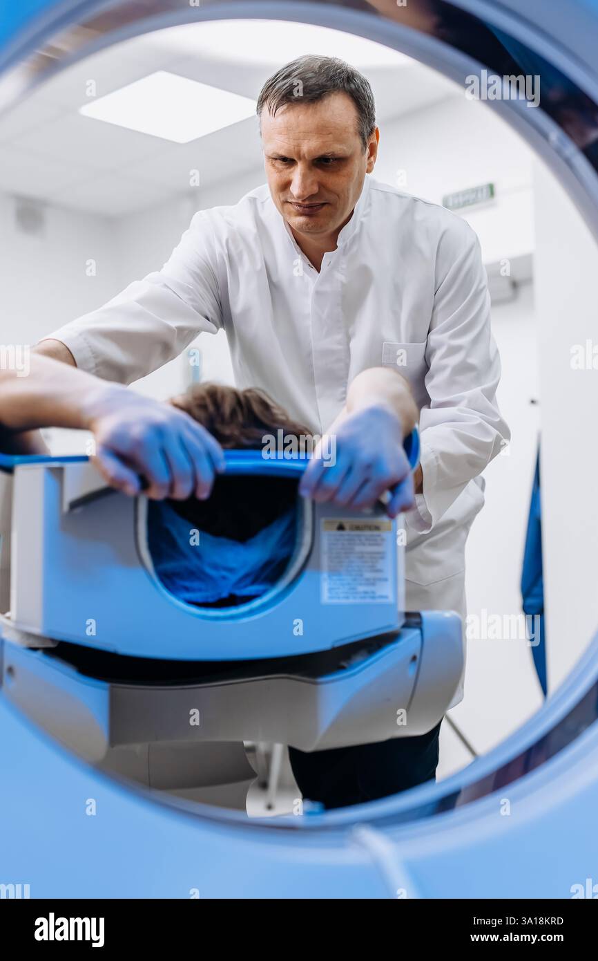 Un médecin dédié effectue un examen IRM tout en s’entretenant avec un patient. Cette image met en valeur le professionnalisme et la compassion dans les soins de santé Banque D'Images