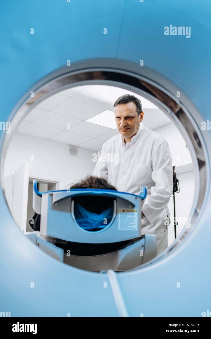 Un médecin dédié effectue un examen IRM tout en s’entretenant avec un patient. Cette image met en valeur le professionnalisme et la compassion dans les soins de santé Banque D'Images